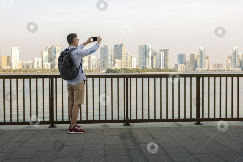 Скачать Мужчина-турист фотографирует центр Шарджи, ОАЭ, и наслаждается видом. фотосток Ozero