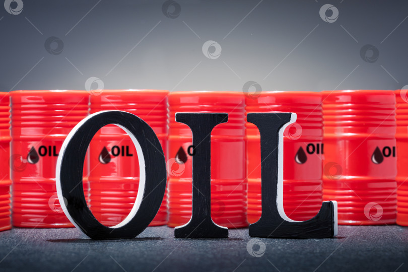 Скачать слово "НЕФТЬ" выполнено черными деревянными буквами и красными бочками с сырой нефтью на заднем плане. фотосток Ozero