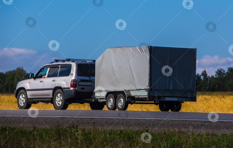 Скачать Автомобиль с прицепом движется по проселочной дороге фотосток Ozero