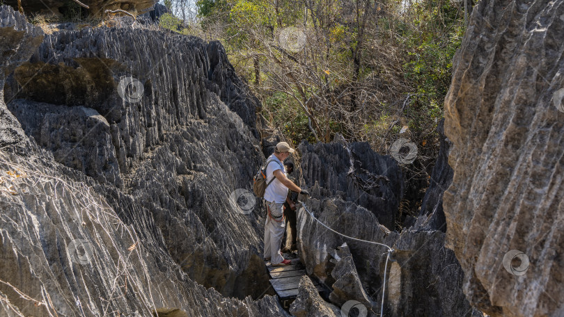 Скачать Мужчина с рюкзаком и спасательным снаряжением стоит на деревянном мосту между скалами фотосток Ozero