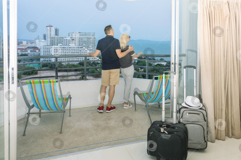 Скачать пара туристов стоит, любуясь прекрасным видом снаружи в гостиничном номере после регистрации заезда. фотосток Ozero