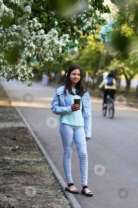 Скачать Молодая девушка прогуливается весной по городскому парку. Аллея цветущих яблонь фотосток Ozero