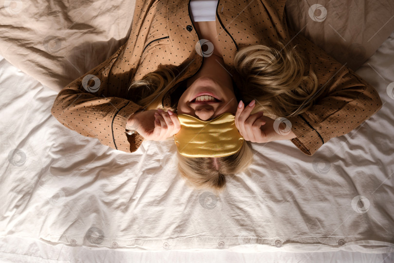 Скачать Игривая женщина улыбается на кровати с повязкой на голове. фотосток Ozero
