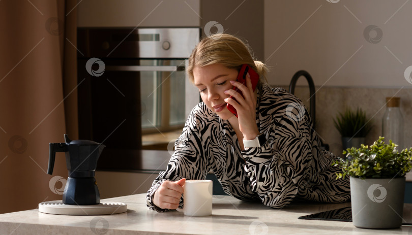 Скачать Женщина разговаривает по телефону, наслаждаясь кофе. фотосток Ozero