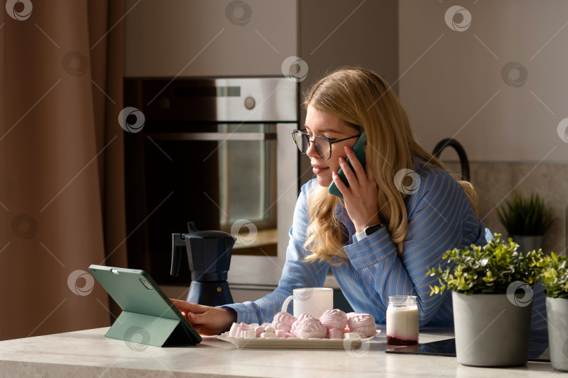 Скачать Женщина разговаривает по телефону с чашкой кофе на кухне фотосток Ozero