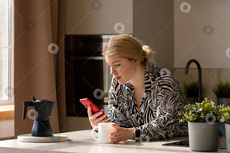 Скачать Женщина, работающая в режиме многозадачности с телефоном и кофе. фотосток Ozero