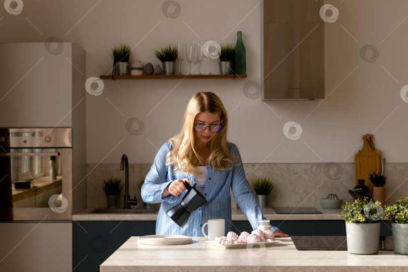 Скачать Женщина разливает кофе на современной кухне фотосток Ozero