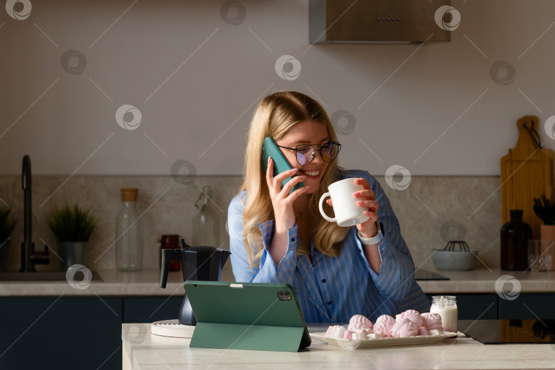 Скачать Женщина, пользующаяся телефоном на кухне с кофе фотосток Ozero