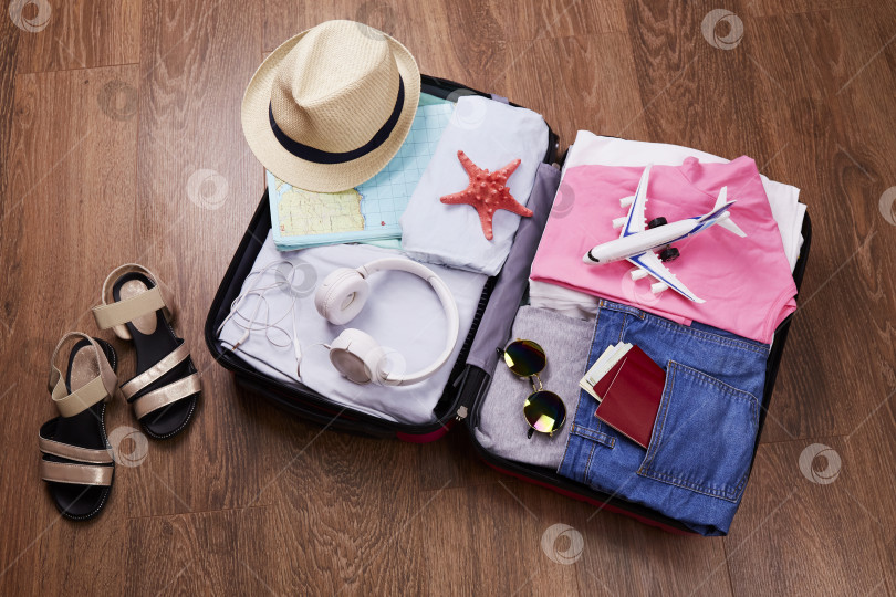 Скачать Открытый чемодан с женскими вещами, паспортом и аксессуарами для отпуска фотосток Ozero