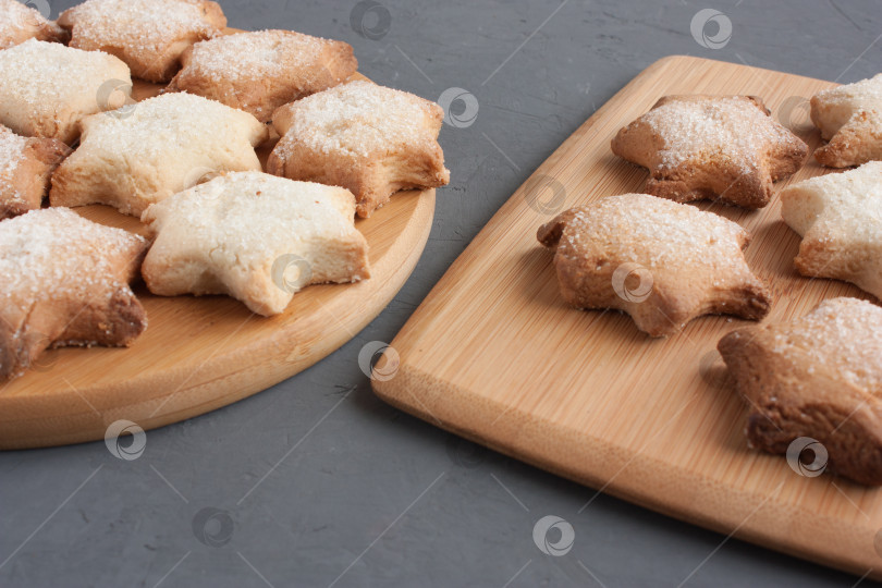 Скачать Вкусное домашнее печенье в форме звездочек, посыпанное сахаром. Выложенный на кухонную доску на темно-сером фоне. фотосток Ozero