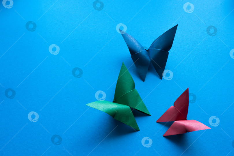 Скачать разноцветные бумажные бабочки оригами на синем бумажном фоне фотосток Ozero