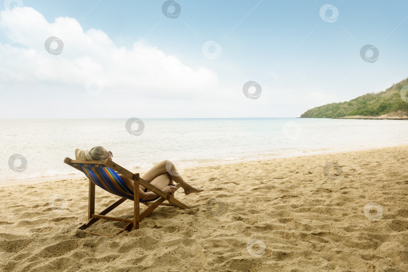 Скачать зрелая женщина отдыхает в шезлонге на тропическом пляже. фотосток Ozero