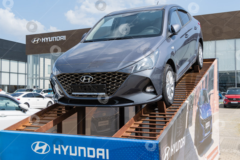 Скачать Автомобиль Hyundai на постаменте возле автосалона Hyundai в Мега Адыгея. Крупный план. Здание автосалона на заднем плане. На фасаде надпись Hyundai. фотосток Ozero