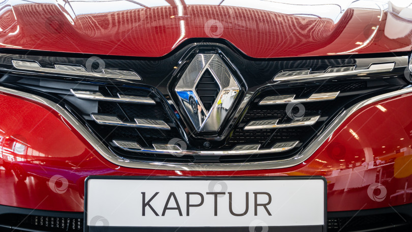 Скачать Красный внедорожник Renault Captur в автосалоне. Крупный план блестящей решетки радиатора с логотипом Renault. Автосалон Renault в Мега Адыгея. фотосток Ozero