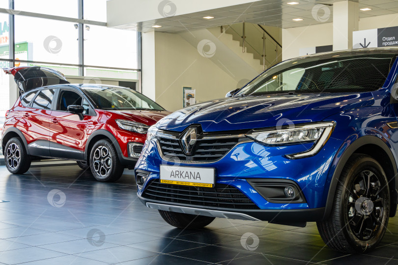 Скачать Синий внедорожник Renault Arkana в автосалоне. Крупный план. На заднем плане красный внедорожник Renault Captur. Автосалон Renault в Мега Адыгея. фотосток Ozero