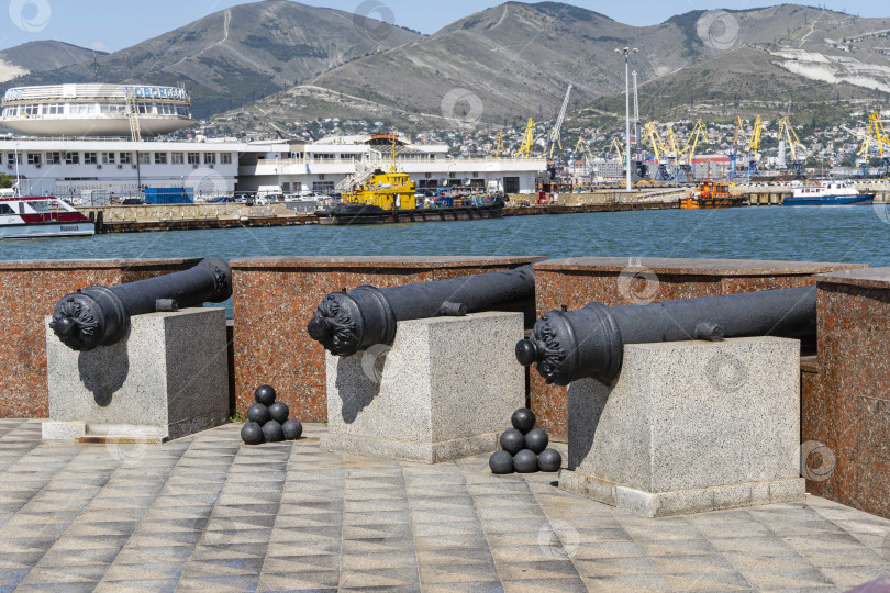 Скачать Установка береговой батареи на смотровой площадке. Три старые пушки направлены в море. Размытый фон терминалов морского торгового порта. фотосток Ozero