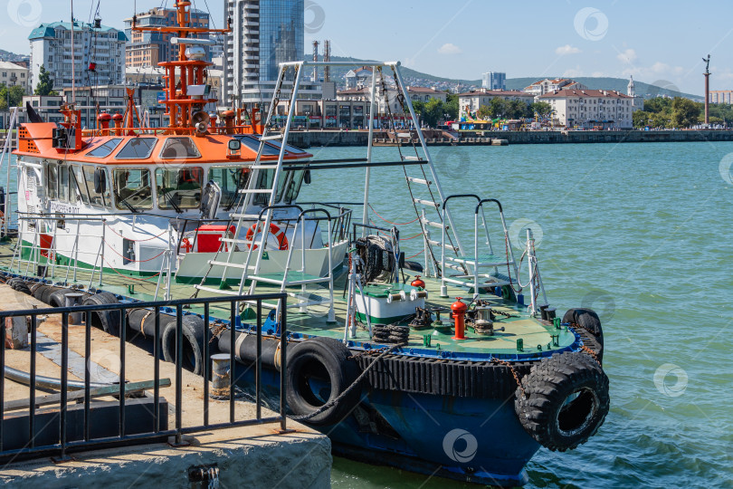 Скачать Буксир Новороссийского морского торгового порта пришвартован к причалу Западного мола. На заднем плане - набережная адмирала Серебрякова. Прогулочная пешеходная зона. фотосток Ozero