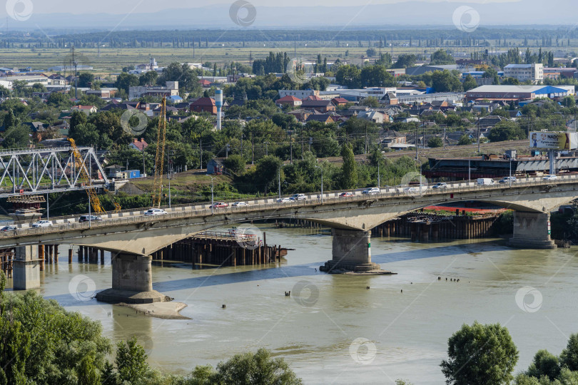 Скачать Движение автомобилей по аварийному автомобильному мосту через реку Кубань. На заднем плане - строительство нового четырехполосного автомобильного моста. Слева - строительство железнодорожного моста. фотосток Ozero