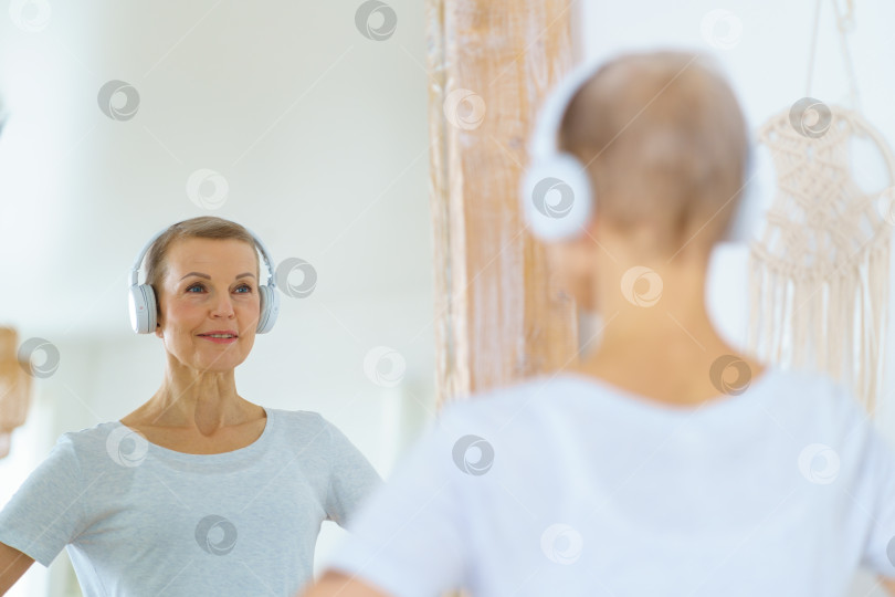 Скачать Спортивная пожилая женщина любуется собой в зеркале. фотосток Ozero