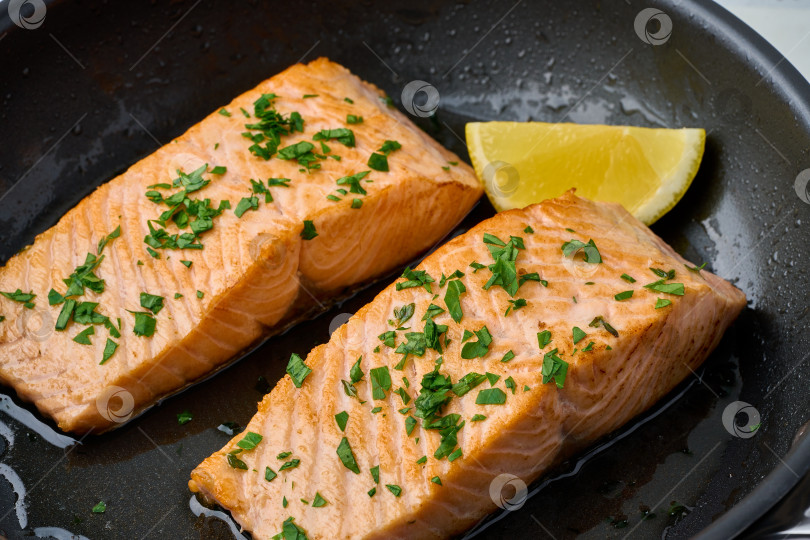 Скачать Крупным планом обжаренное сочное филе лосося с петрушкой и лимоном на сковороде фотосток Ozero