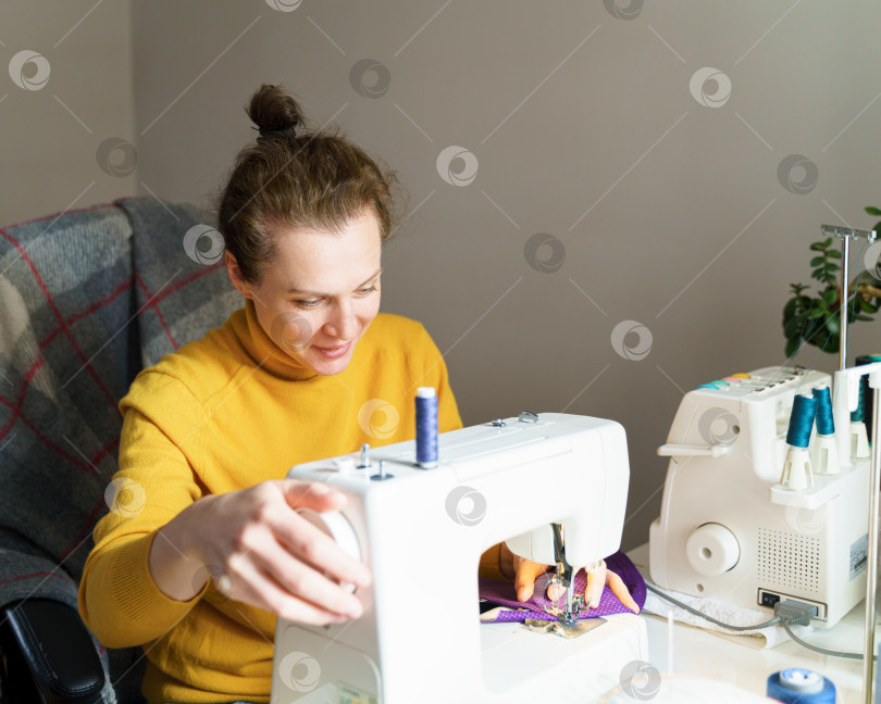Скачать Женщина-швея, использующая швейную машинку во время работы дома фотосток Ozero