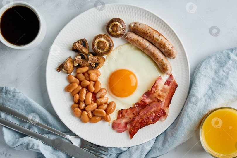 Скачать Классический английский завтрак с яйцами, сосисками, беконом, фасолью, грибами, кофе и апельсиновым соком фотосток Ozero
