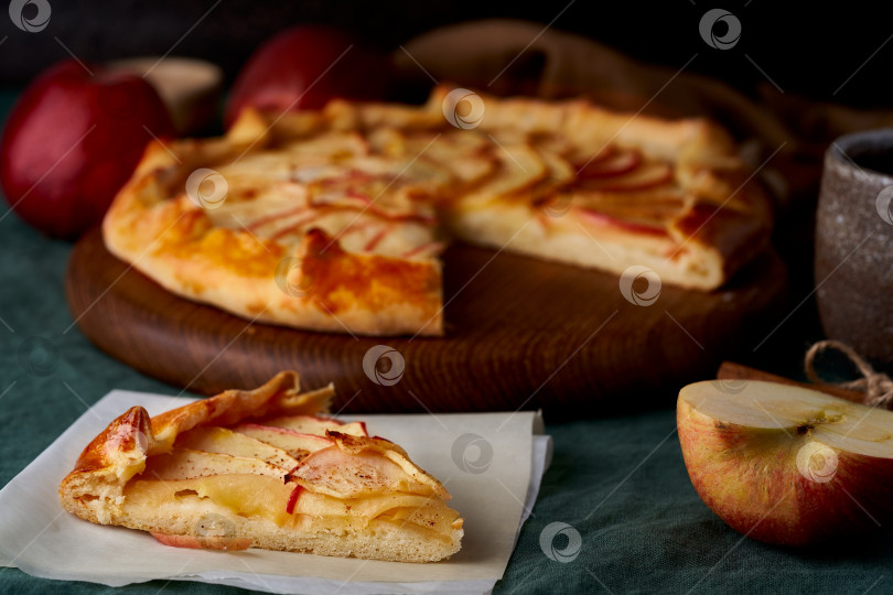 Скачать Яблочный пирог с кусочками галета с фруктами, нарезанная сладкая выпечка на темно-зеленой скатерти фотосток Ozero