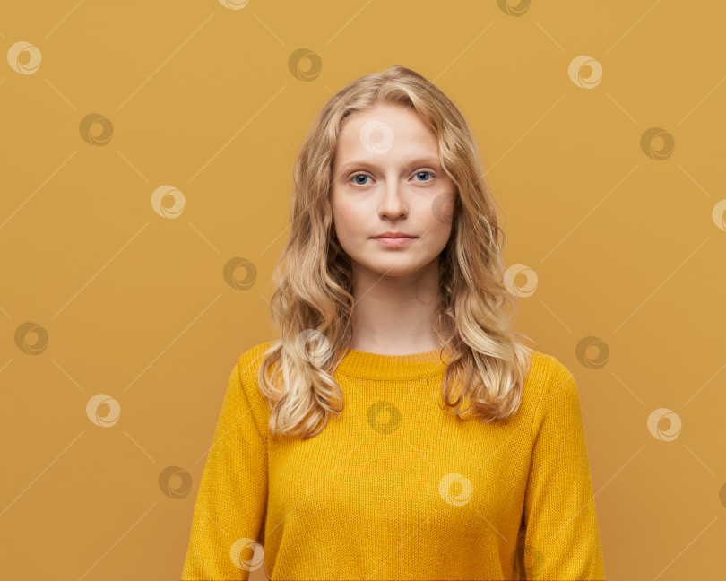 Скачать Портрет красивой молодой серьезной умной блондинки-скандинавки по пояс на ярко-желто-оранжевой стене фотосток Ozero