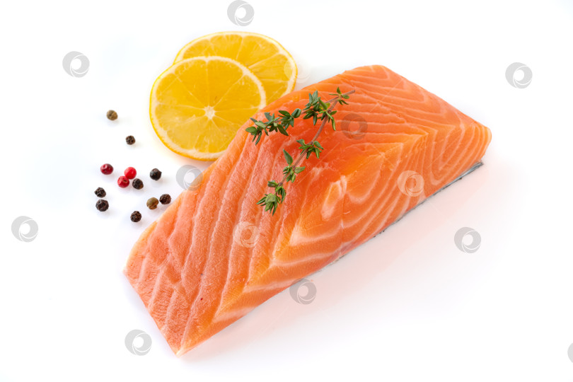 Скачать Стейк из свежего сырого филе лосося, нарезанный ломтиками на белом фоне, с приправой и лимоном фотосток Ozero