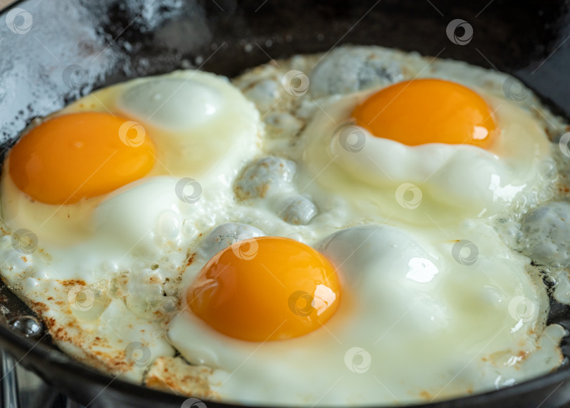Скачать Кето-блюдо, жарка яиц на раскаленной чугунной сковороде, три обжаренных желтка, кетогенная диета фотосток Ozero