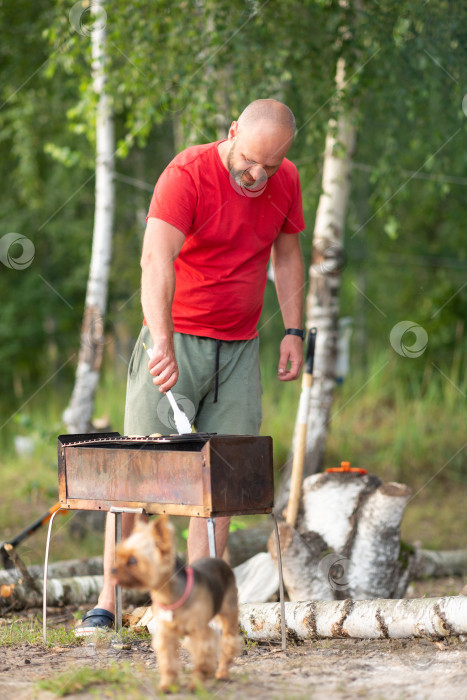 Скачать Мужчина готовит овощи на мангале в палаточном лагере фотосток Ozero