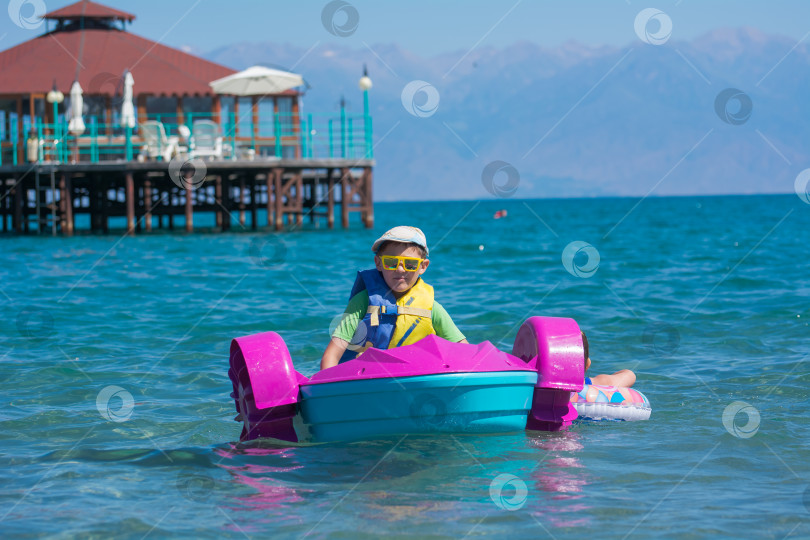 Скачать Ребенок 5-8 лет катается по морю на водной детской лодке. фотосток Ozero