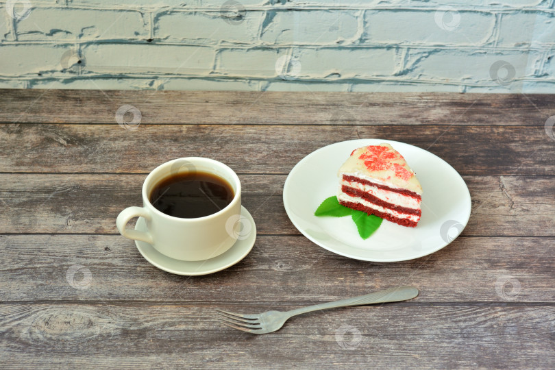 Скачать Тарелка с ломтиком торта "красный бархат" с листьями мяты и чашкой черного кофе на столе из светлого дерева. фотосток Ozero