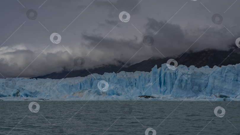 Скачать Стена голубого льда с трещинами, расселинами и острыми пиками простирается в ледниковом бирюзовом озере. фотосток Ozero