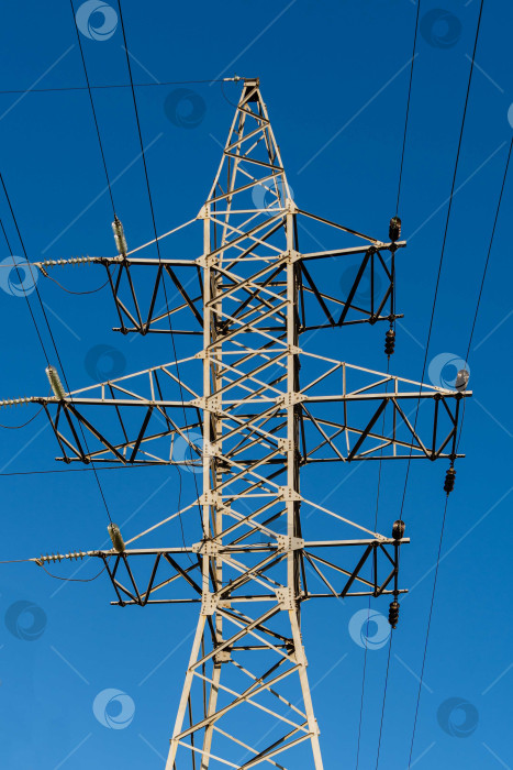 Скачать Двухконтурная башня воздушной линии электропередачи на фоне голубого неба. Стальная конструкция с широким основанием внизу. Изоляторы на опорах из стекла, фарфора. фотосток Ozero