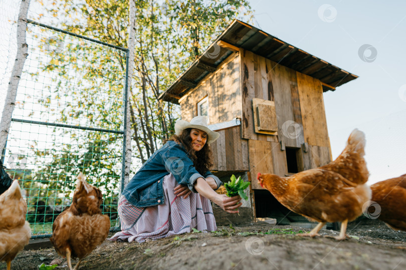 Скачать Улыбающаяся женщина наслаждается жизнью на ферме, кормя своих цыплят фотосток Ozero