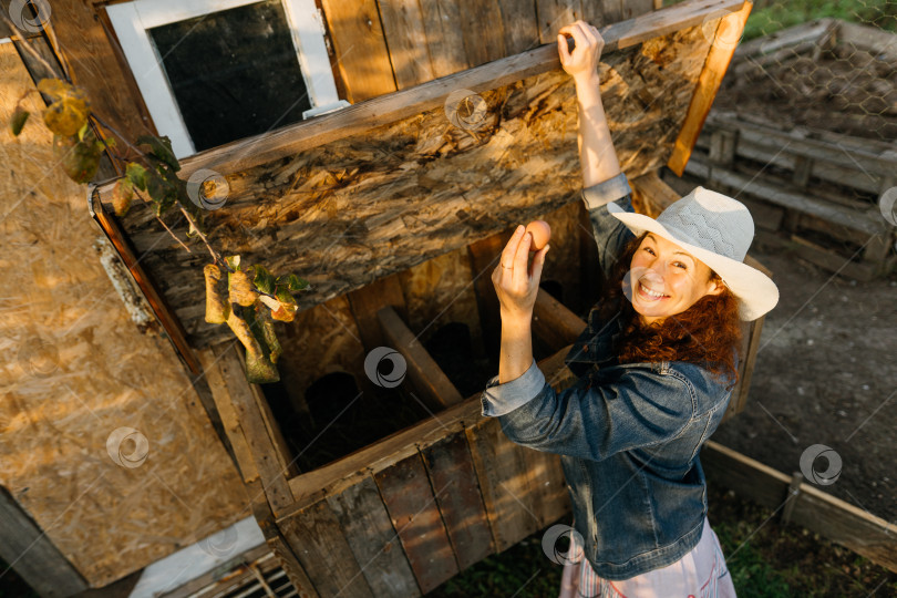 Скачать Наслаждаясь сельским хозяйством, женщина-фермер поднимает в воздух свежее яйцо. фотосток Ozero