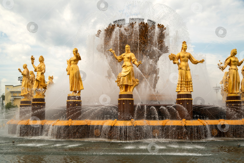 Скачать Июль 2022 года, Москва, Россия - фрагмент знаменитого фонтана "Дружба народов" на ВДНХ с золотыми статуями, расположенными по кругу фотосток Ozero