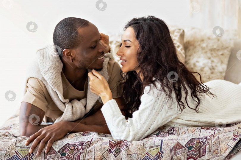 Скачать Влюбленная пара - чернокожий мужчина и мулатка на кровати в светлой комнате. Разнообразная семья фотосток Ozero