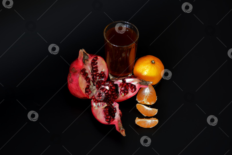 Скачать Стакан сока из смеси граната и мандарина на черном фоне, рядом со спелыми фруктами. фотосток Ozero