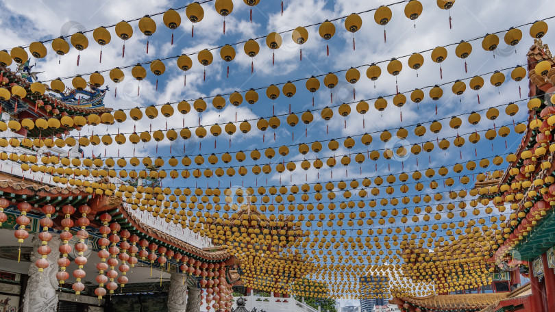 Скачать Ряды ярко-желтых и красных китайских фонариков на фоне голубого неба и облаков. фотосток Ozero