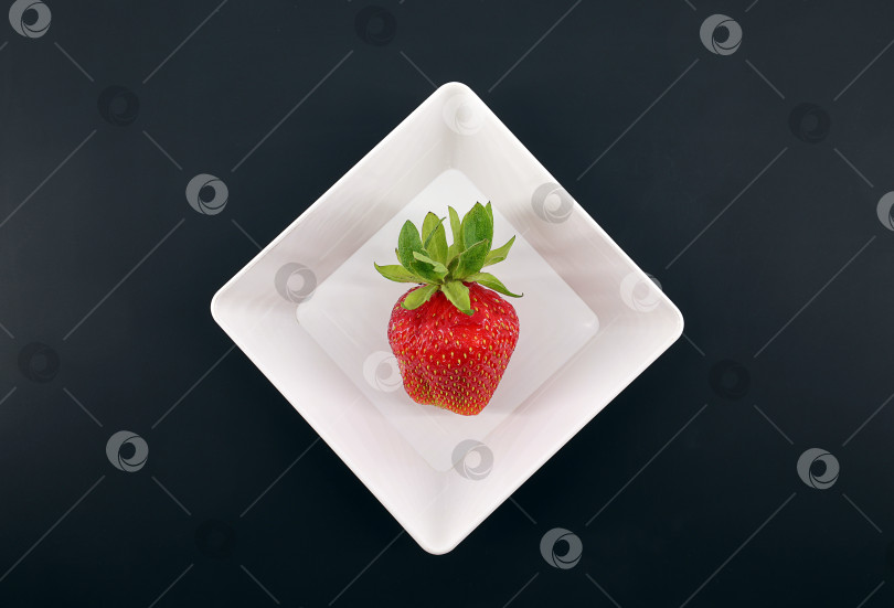 Скачать ягода клубники лежит в квадратной тарелке на черном фоне фотосток Ozero