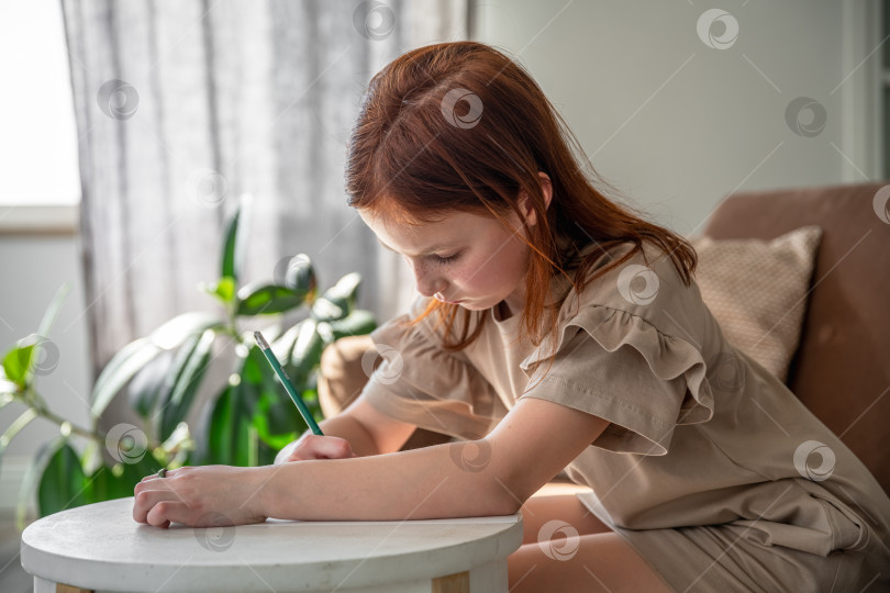 Скачать милая маленькая девочка-подросток рисует ручкой, сидя дома за письменным столом, красивая девочка женского пола, маленький ребенок делает школьную домашнюю работу фотосток Ozero