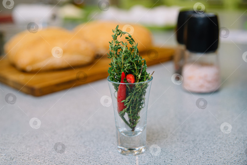 Скачать Свежая зелень в бокале и выпеченный хлеб на кухонном столе фотосток Ozero