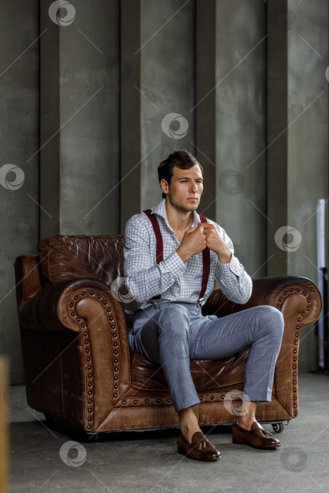 Скачать Молодой бизнесмен размышляет после встречи, позируя перед камерой в деловой официальной одежде, сидя в кресле фотосток Ozero