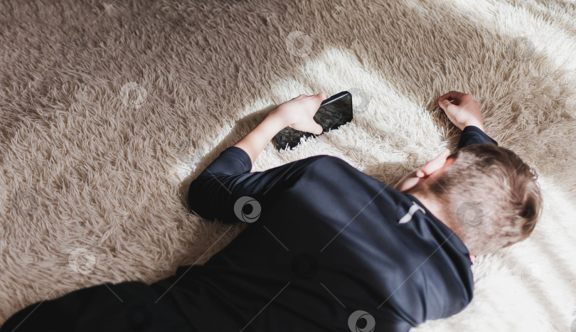 Скачать Изображение маленького мальчика в помещении, сидящего на диване с телефоном фотосток Ozero