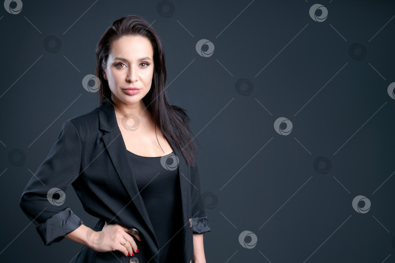 Скачать Женщина в черном пиджаке и черной рубашке стоит впереди на темном фоне фотосток Ozero