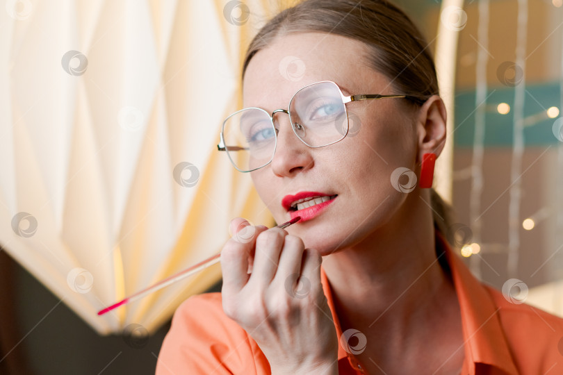 Скачать Женщина в очках красит губы губной помадой фотосток Ozero