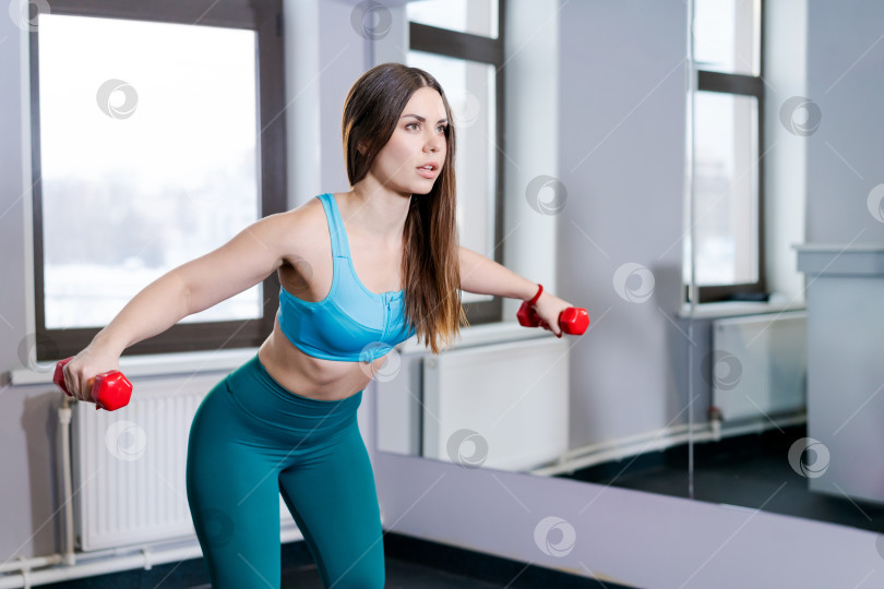 Скачать Женщина тренируется с гантелями в тренажерном зале фотосток Ozero