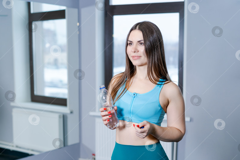 Скачать Женщина в синей майке держит в руках бутылку воды фотосток Ozero